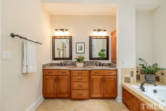 a bathroom with a granite countertop double vanity sink a mirror and a bathtub