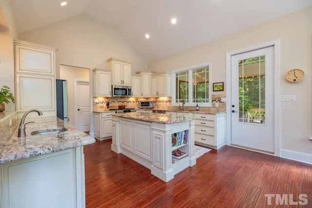 a kitchen with stainless steel appliances granite countertop wooden floors and white cabinets