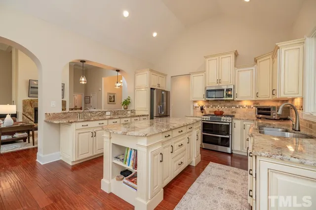 a kitchen with stainless steel appliances granite countertop a stove top oven a sink dishwasher a refrigerator and white cabinets with wooden floor