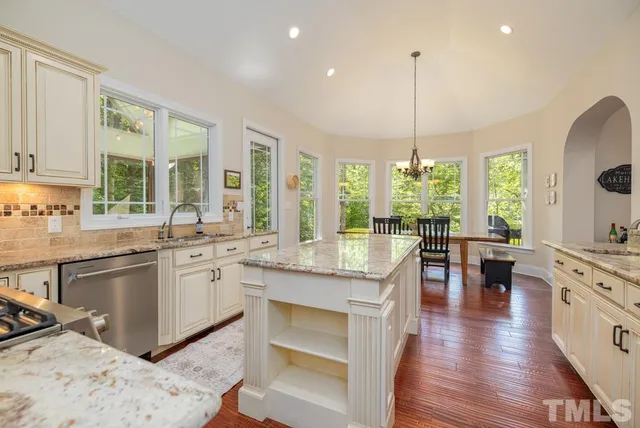 a kitchen with stainless steel appliances granite countertop a stove top oven a sink dishwasher a dining table and chairs with wooden floor