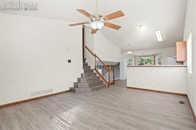 4763 Brant Road Colorado Springs, CO 80911 - Photo 5 of 26 Unfurnished living room with ceiling fan, light wood-type flooring, and vaulted ceiling