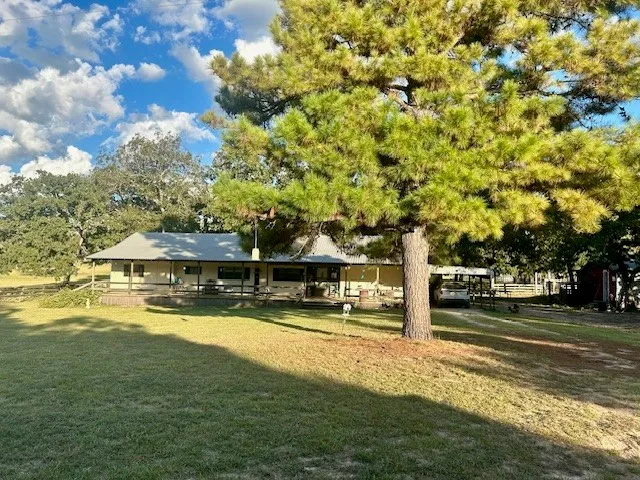 a view of a swimming pool with a lawn chairs and large trees