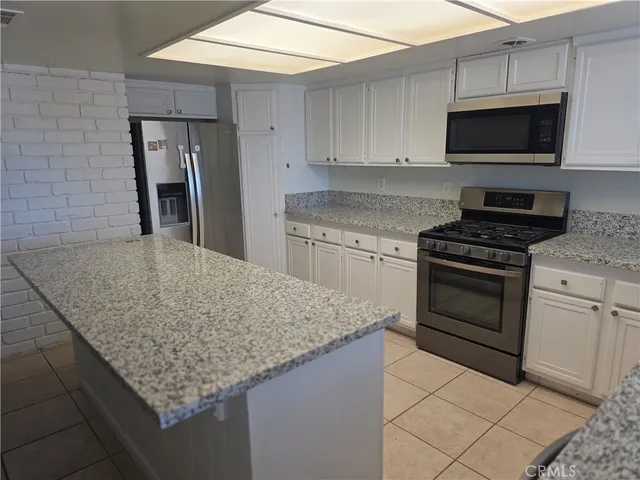 a kitchen with granite countertop stainless steel appliances a stove microwave and sink