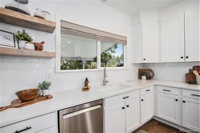 a kitchen with white cabinets and a window