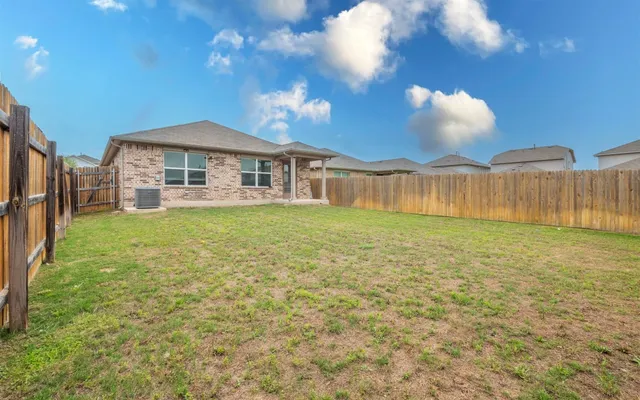 a view of a house with a yard and a large tree