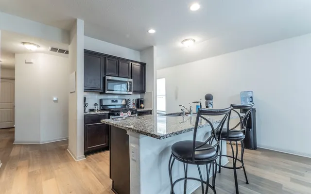a kitchen with granite countertop wooden floor cabinets and stainless steel appliances