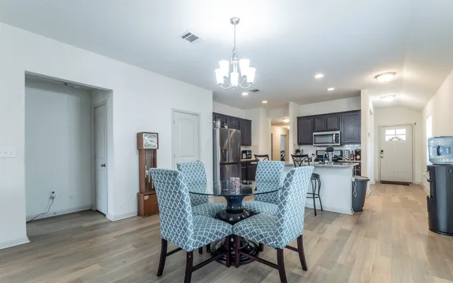 a view of a dining room and livingroom with furniture wooden floor a chandelier