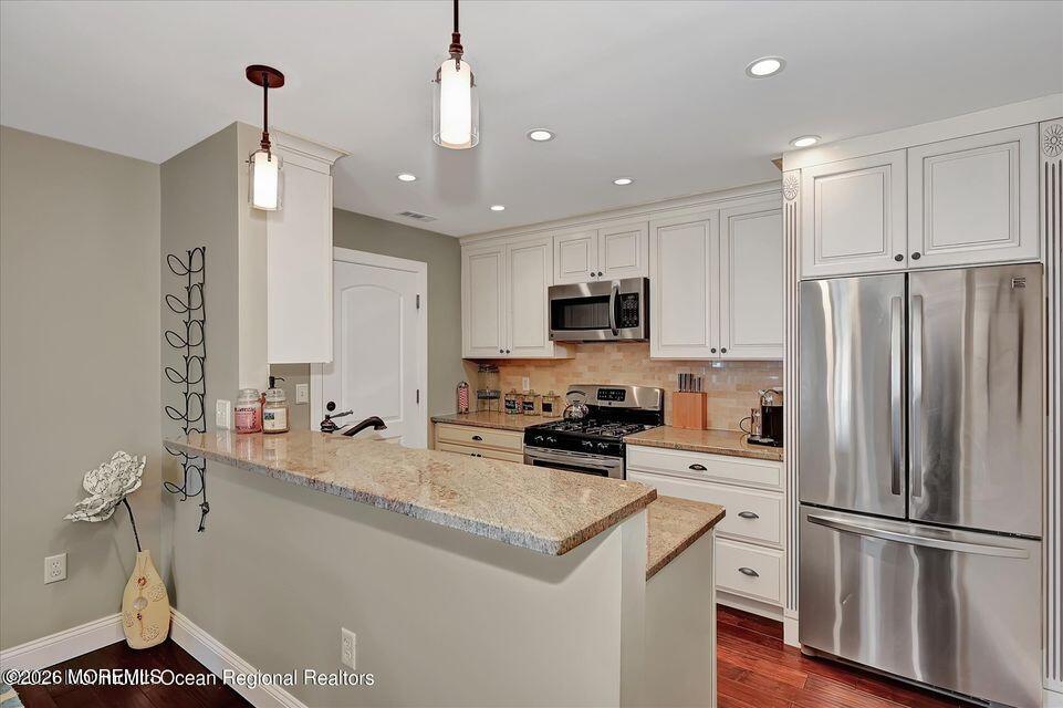 13 Racquet Road Wall, NJ 07719 - Photo 3 of 20 a kitchen with kitchen island granite countertop a refrigerator a sink dishwasher a stove and white cabinets with wooden floor