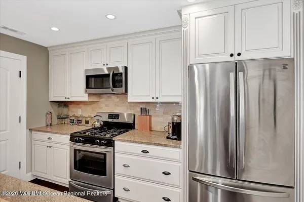 a kitchen with white cabinets and stainless steel appliances