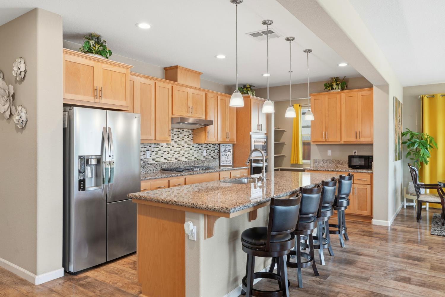 1816 Fire Power Avenue Manteca, CA 95337 - Photo 14 of 38 a kitchen with stainless steel appliances granite countertop a refrigerator a oven a sink a dining table and chairs with wooden floor