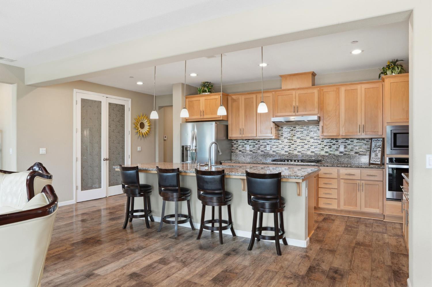 1816 Fire Power Avenue Manteca, CA 95337 - Photo 16 of 38 a kitchen with stainless steel appliances granite countertop a stove a sink a dining table and chairs
