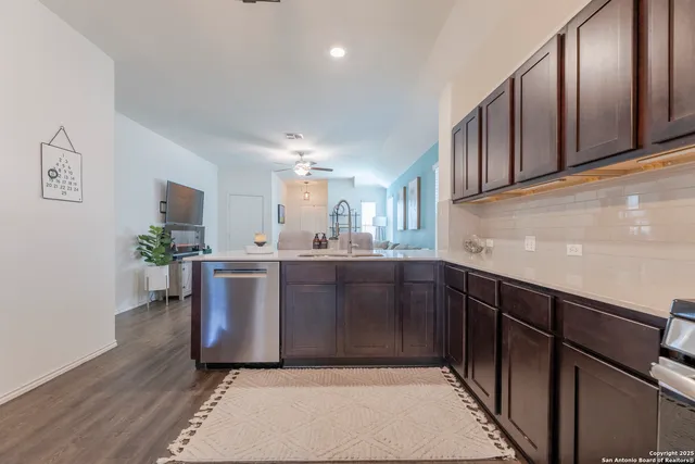 a kitchen with granite countertop wooden floors stainless steel appliances and sink