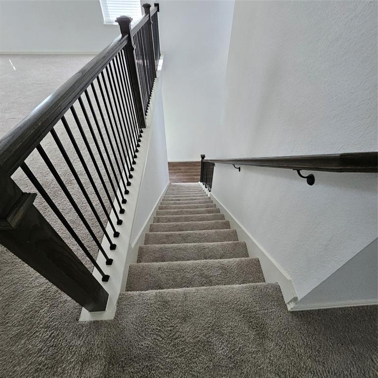 2309 Jack Rabbit Way Northlake, TX 76247 - Photo 13 of 28 Staircase featuring dark wood handrails, black metal balusters, and light gray carpeted steps