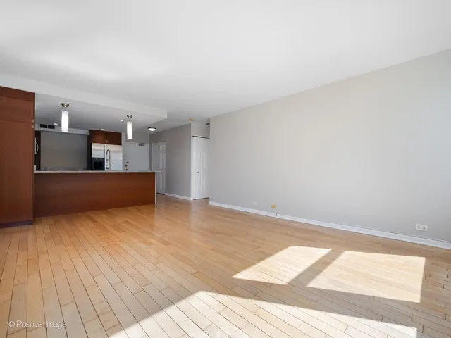 a view of a room with wooden floor and kitchen view