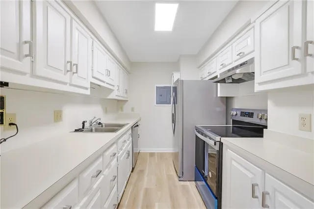 a kitchen with stainless steel appliances a sink dishwasher stove refrigerator and cabinets
