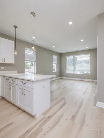 a large kitchen with kitchen island white cabinets and wooden floor