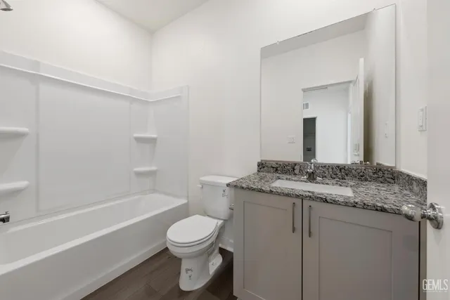 a bathroom with a granite countertop toilet sink and mirror