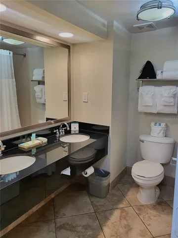 a bathroom with a granite countertop toilet sink and mirror