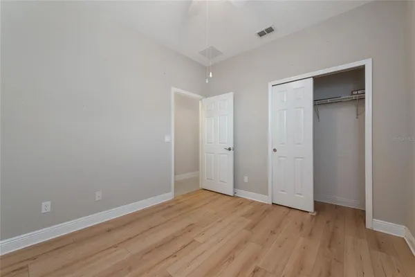 a view of an empty room with wooden floor and closet