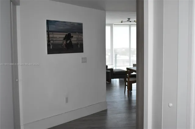 a view of a hallway with wooden floor and a dining room