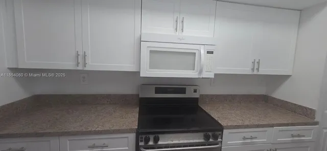 a kitchen with granite countertop white cabinets and white appliances