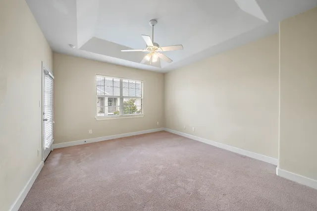 an empty room with windows and ceiling fan