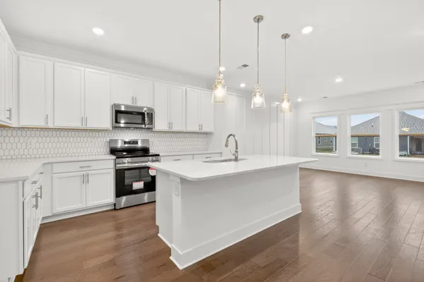 a view of a kitchen with a refrigerator a sink and a wooden floor