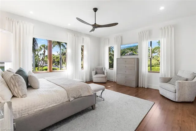 a bedroom with a bed couch and windows