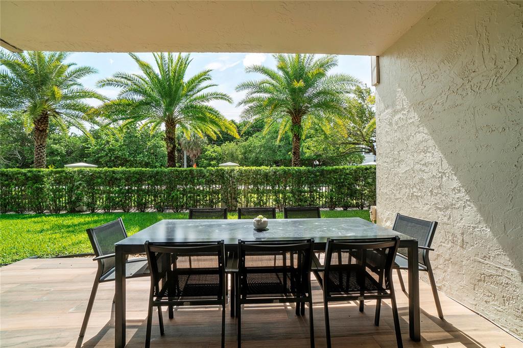 3908 South Ocean Boulevard, Unit TH4 Boca Raton, FL 33487 - Photo 24 of 37 a table and chairs in front of a yard