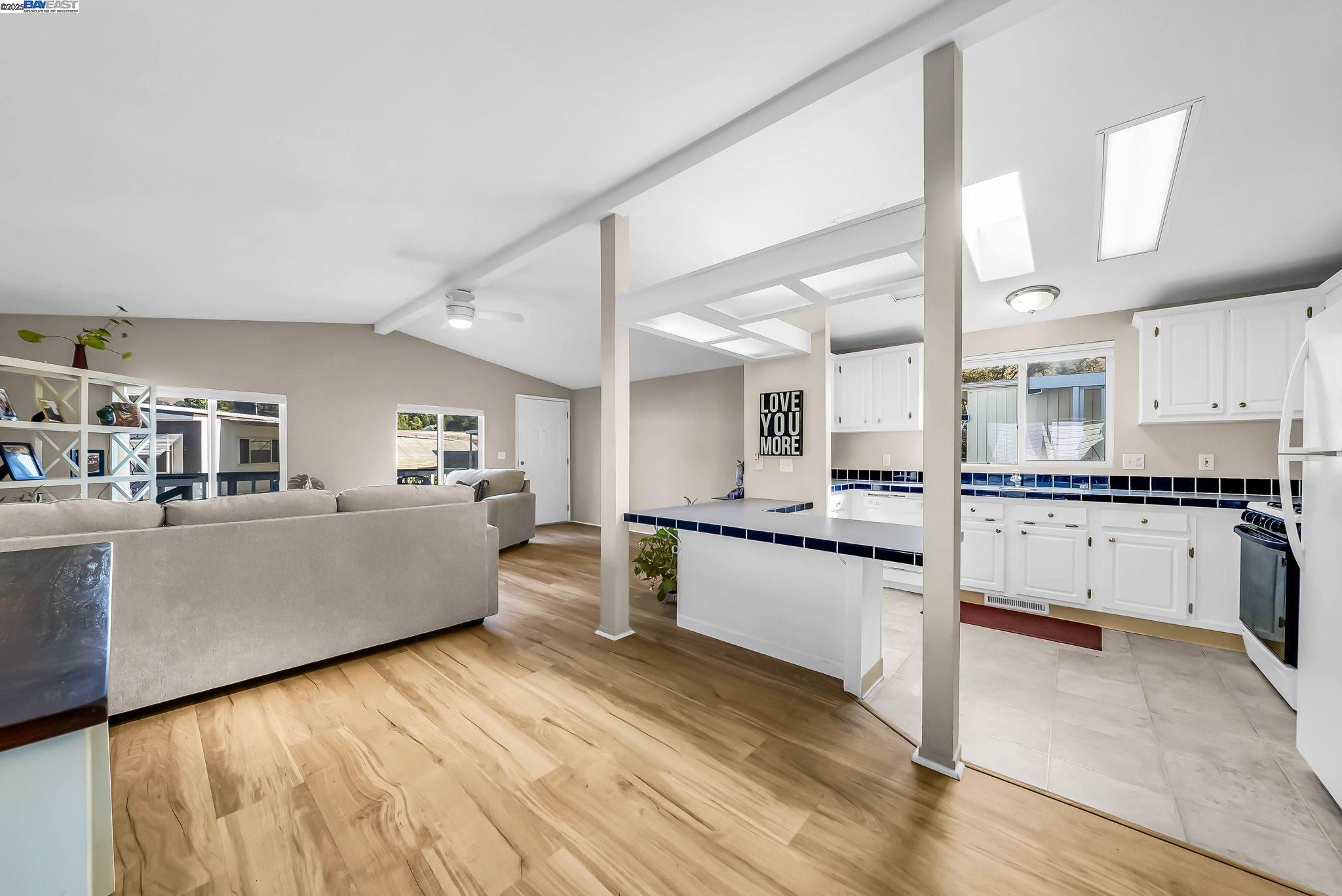 711 Old Canyon Road, Unit 176 Fremont, CA 94536 - Photo 14 of 41 a large white kitchen with kitchen island a stove a sink dishwasher and white cabinets with wooden floor