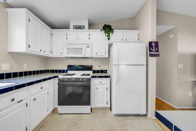a kitchen with granite countertop white cabinets and white appliances