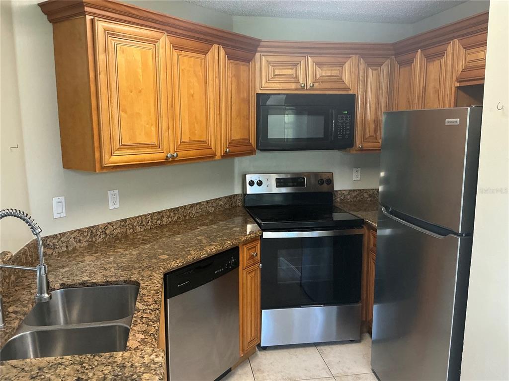 715 Sugar Bay Way, Unit 107 Lake Mary, FL 32746 - Photo 3 of 48 a kitchen with stainless steel appliances granite countertop a refrigerator stove and microwave