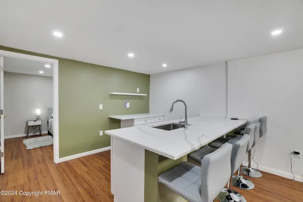 a view of kitchen island a sink a wooden floor and a kitchen view