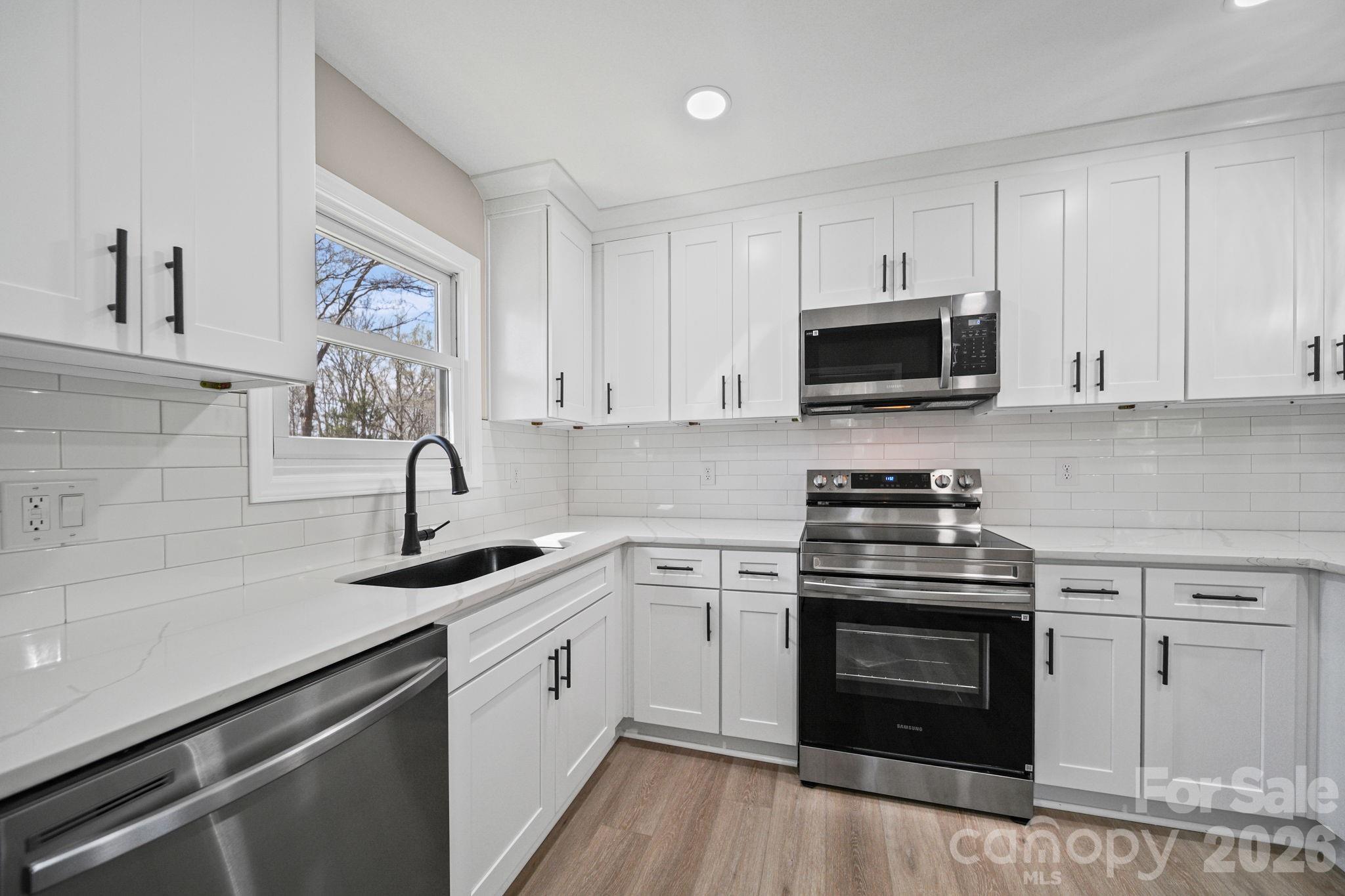 5808 Flint Ridge Marshville, NC 28103 - Photo 11 of 38 a kitchen with white cabinets and stainless steel appliances