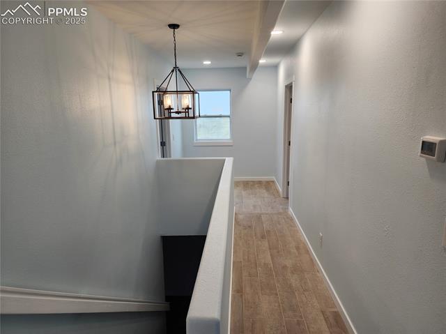 32174 Torrence Road Yoder, CO 80864 - Photo 11 of 13 Corridor featuring baseboards, a notable chandelier, recessed lighting, and wood finished floors