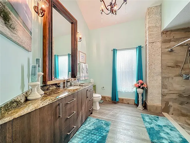 a bathroom with a granite countertop toilet sink and mirror