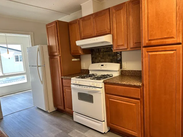 a kitchen with granite countertop wood cabinets and a stove top oven