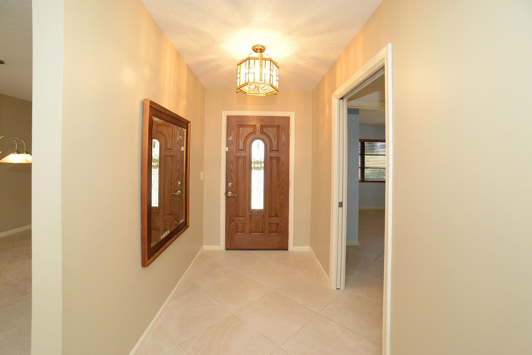17290 Lake Park Road Boca Raton, FL 33487 - Photo 18 of 28 a view of a hallway with wooden floor and a chandelier