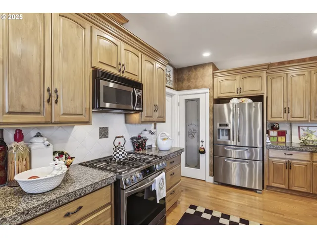 a kitchen with stainless steel appliances granite countertop a refrigerator and a stove top oven