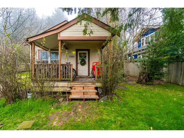 a view of a house with a small yard plants and large tree