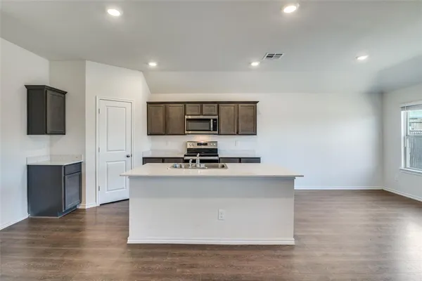 a kitchen with stainless steel appliances a stove top oven a sink a refrigerator a window