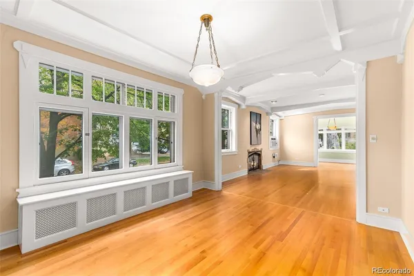 a view of an empty room with window and kitchen view