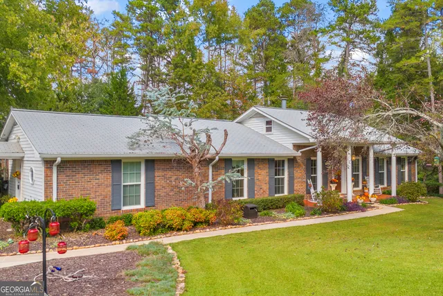 a front view of a house with garden and trees