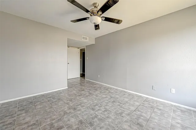 an empty room with a ceiling fan and carpet