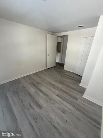 a view of an empty room with wooden floor and closet