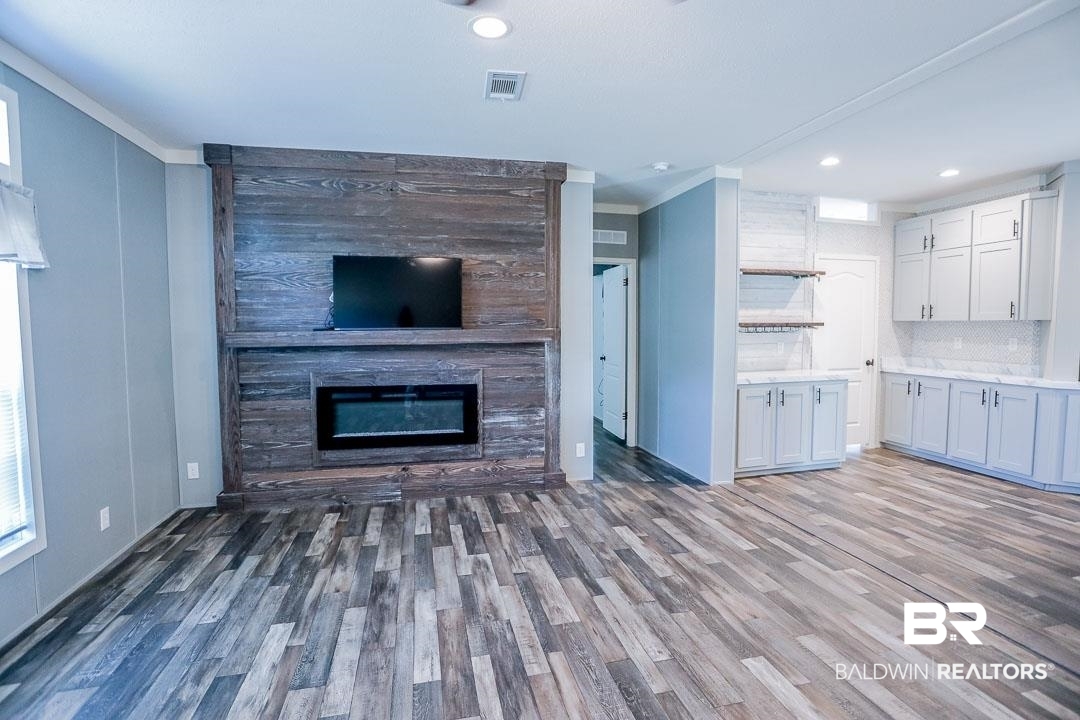 19180 Horseshoe Circle Seminole, AL 36574 - Photo 2 of 38 Unfurnished living room with dark wood-type flooring, crown molding, a glass covered fireplace, and recessed lighting