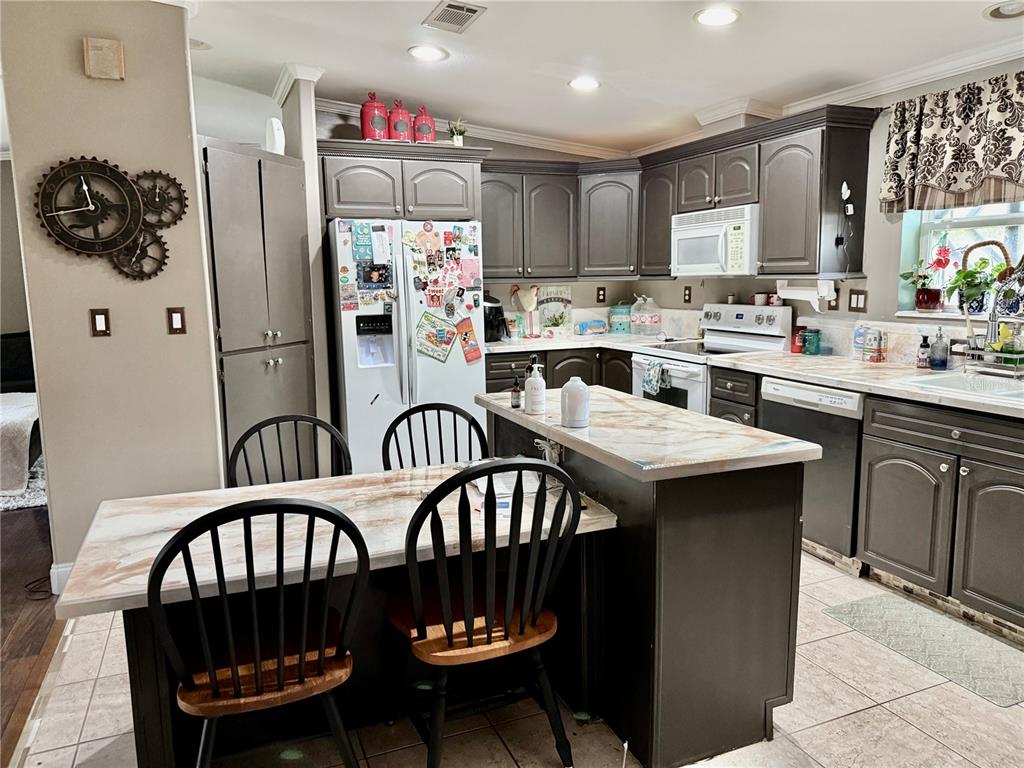 5321 South June Terrace, Unit 74 Homosassa, FL 34446 - Photo 16 of 28 a kitchen with a refrigerator a sink dishwasher a dining table and chairs with wooden floor