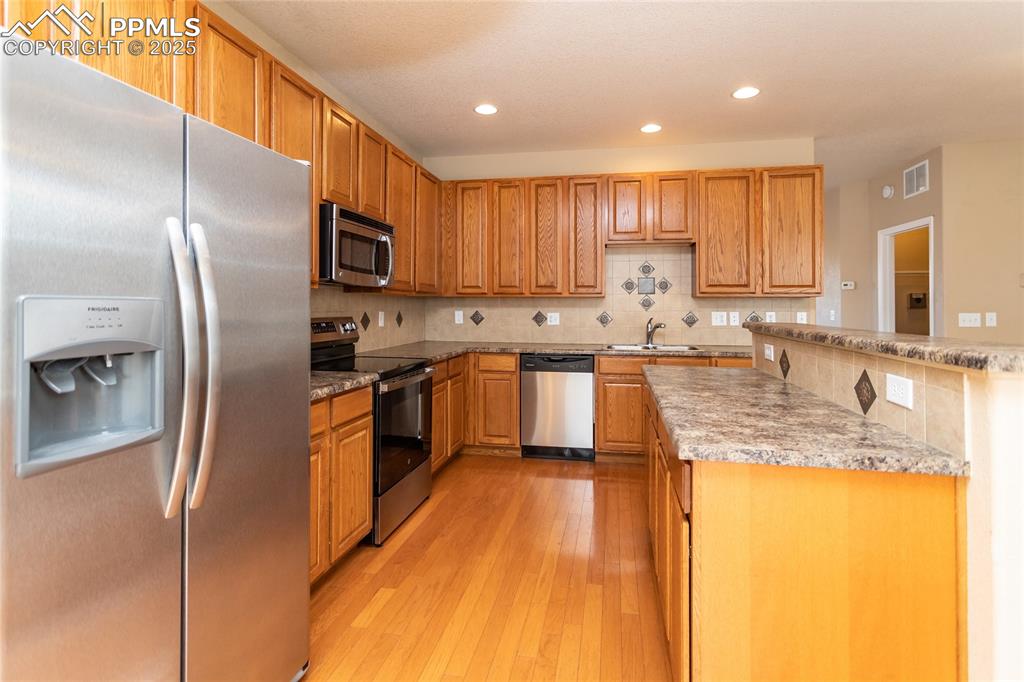 4829 Harrier Ridge Drive Colorado Springs, CO 80916 - Photo 12 of 50 a large kitchen with stainless steel appliances granite countertop a sink a stove and a refrigerator