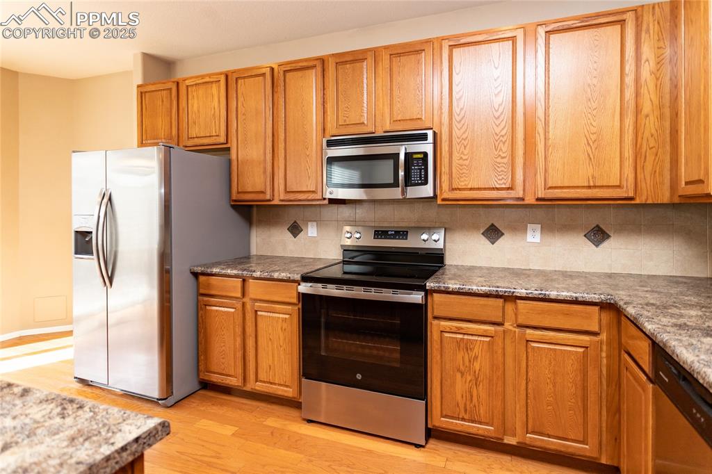 4829 Harrier Ridge Drive Colorado Springs, CO 80916 - Photo 14 of 50 a kitchen with stainless steel appliances granite countertop a stove a refrigerator and a cabinets