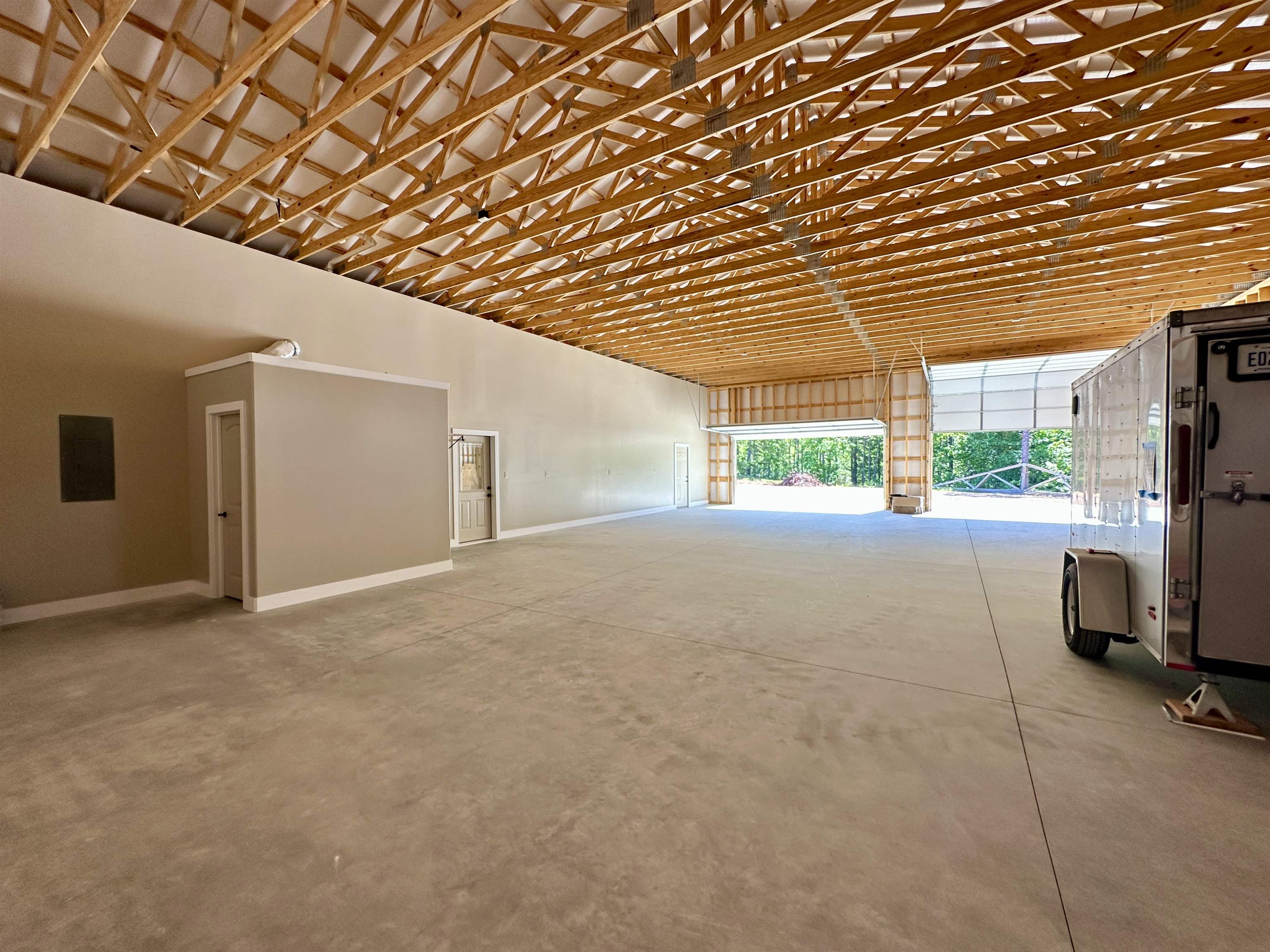1137 Arl Bailey Road Finger, TN 38334 - Photo 25 of 40 Spacious unfinished interior featuring exposed wood truss ceiling, concrete flooring, and multiple roll-up door openings